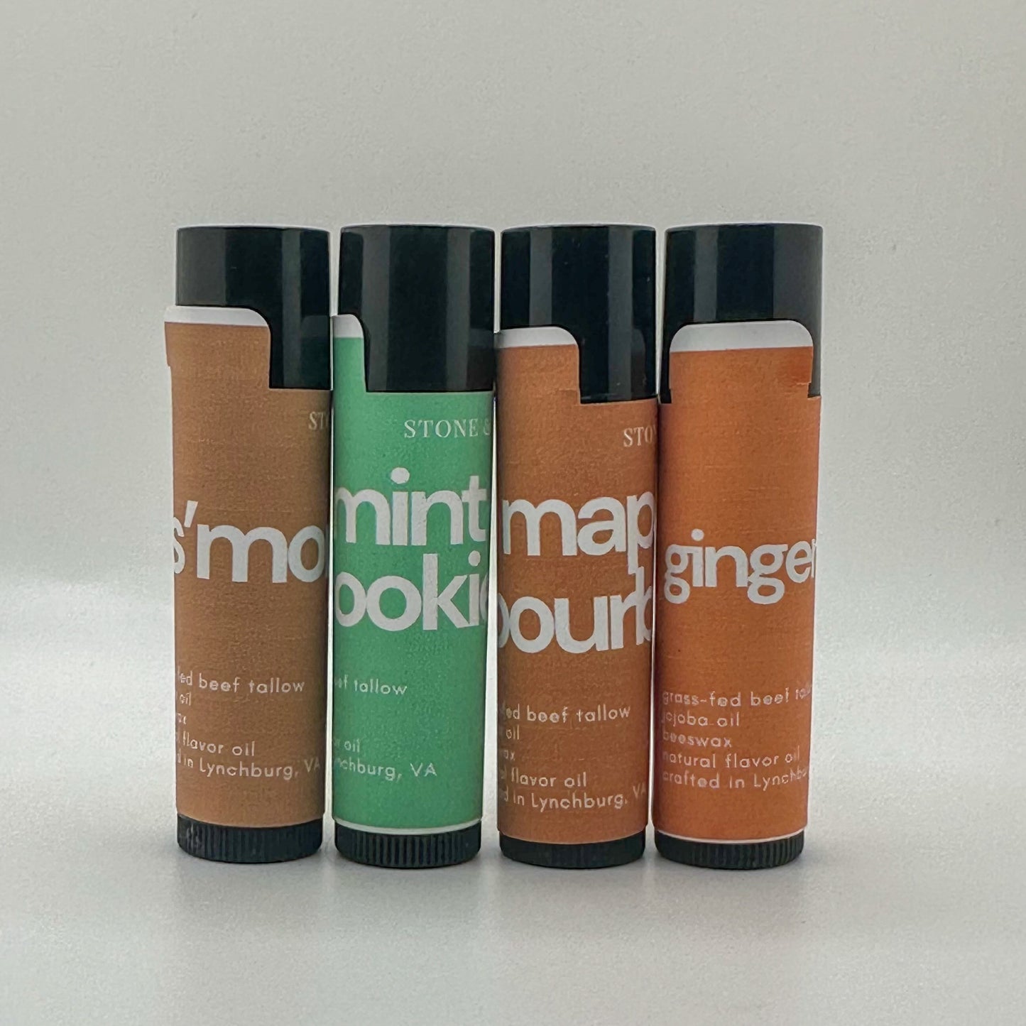 Four cylindrical lip balm containers with labels on a white background