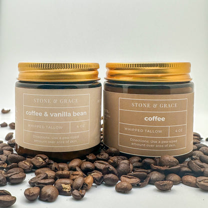 Two jars of Stone & Grace whipped tallow with gold lids on coffee beans. Scents are coffee themed.
