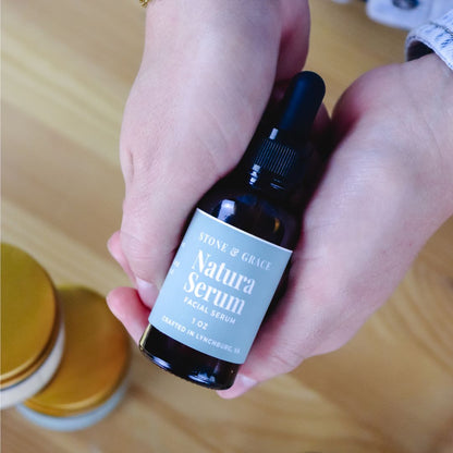 Pair of hands holding a bottle of Natura Serum by Stone& Grace.