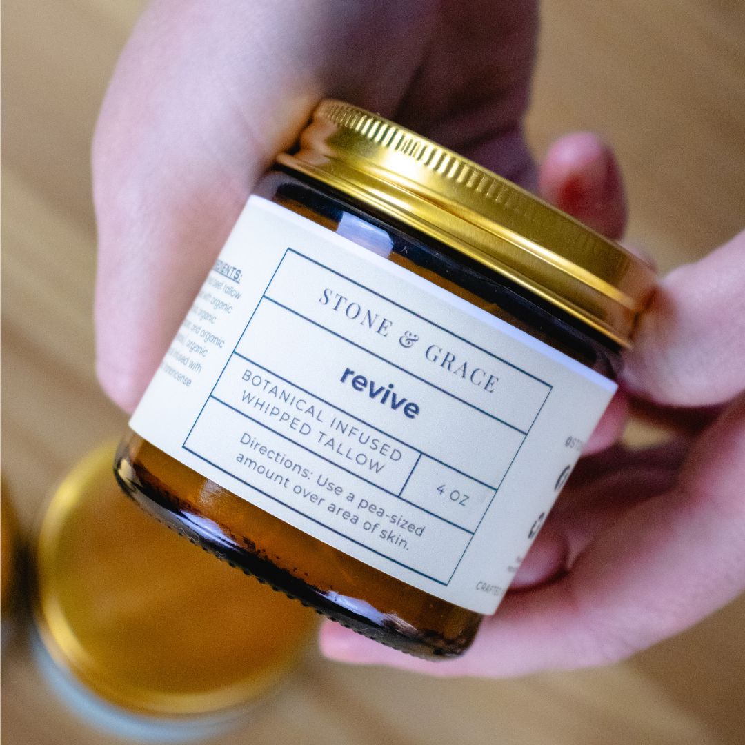 Hand holding a jar of 'Stone & Grace' revive botanical infused whipped tallow balm.