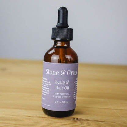 Bottle of Stone & Grace Scalp and Hair Oil on a wooden surface with a light gray background