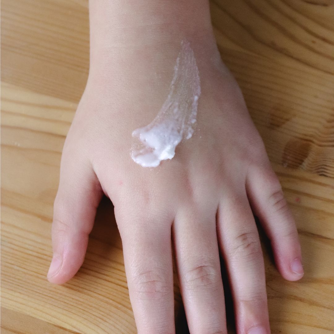 Hand with a small amount of cream on a wooden surface