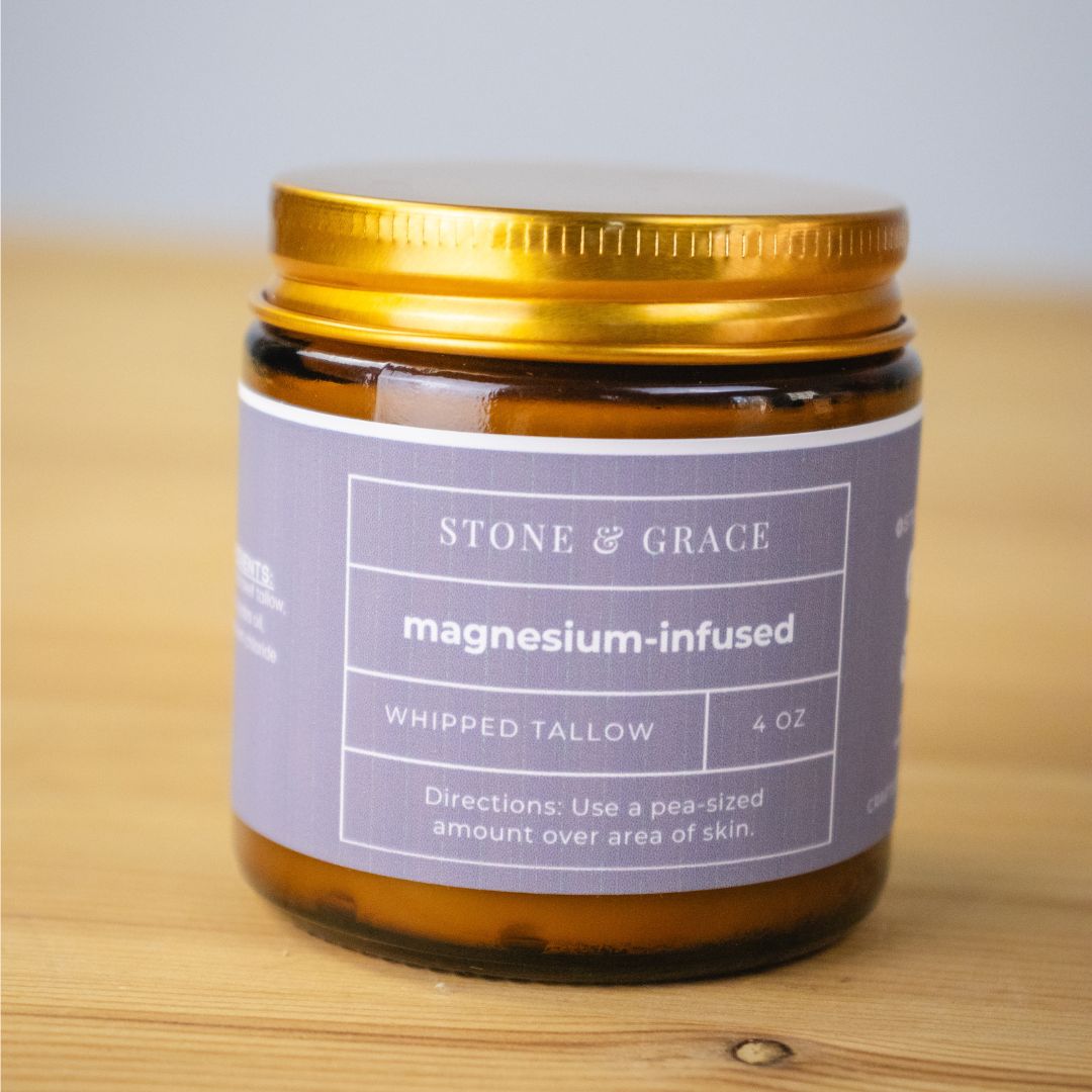 Jar of Stone & Grace magnesium-infused whipped tallow on a wooden surface