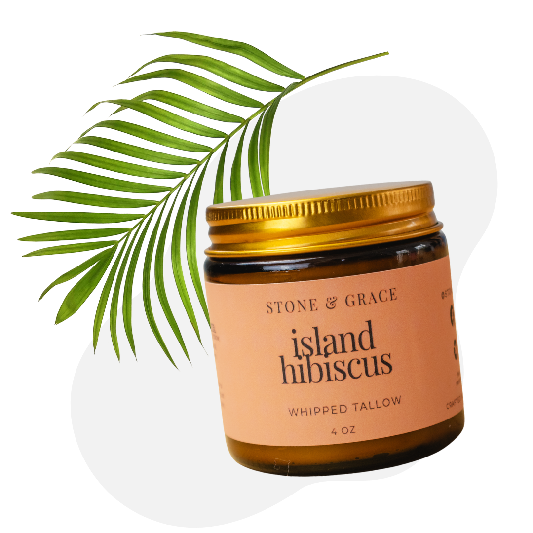 Jar of Stone & Grace Island Hibiscus whipped tallow with a palm leaf on a white background