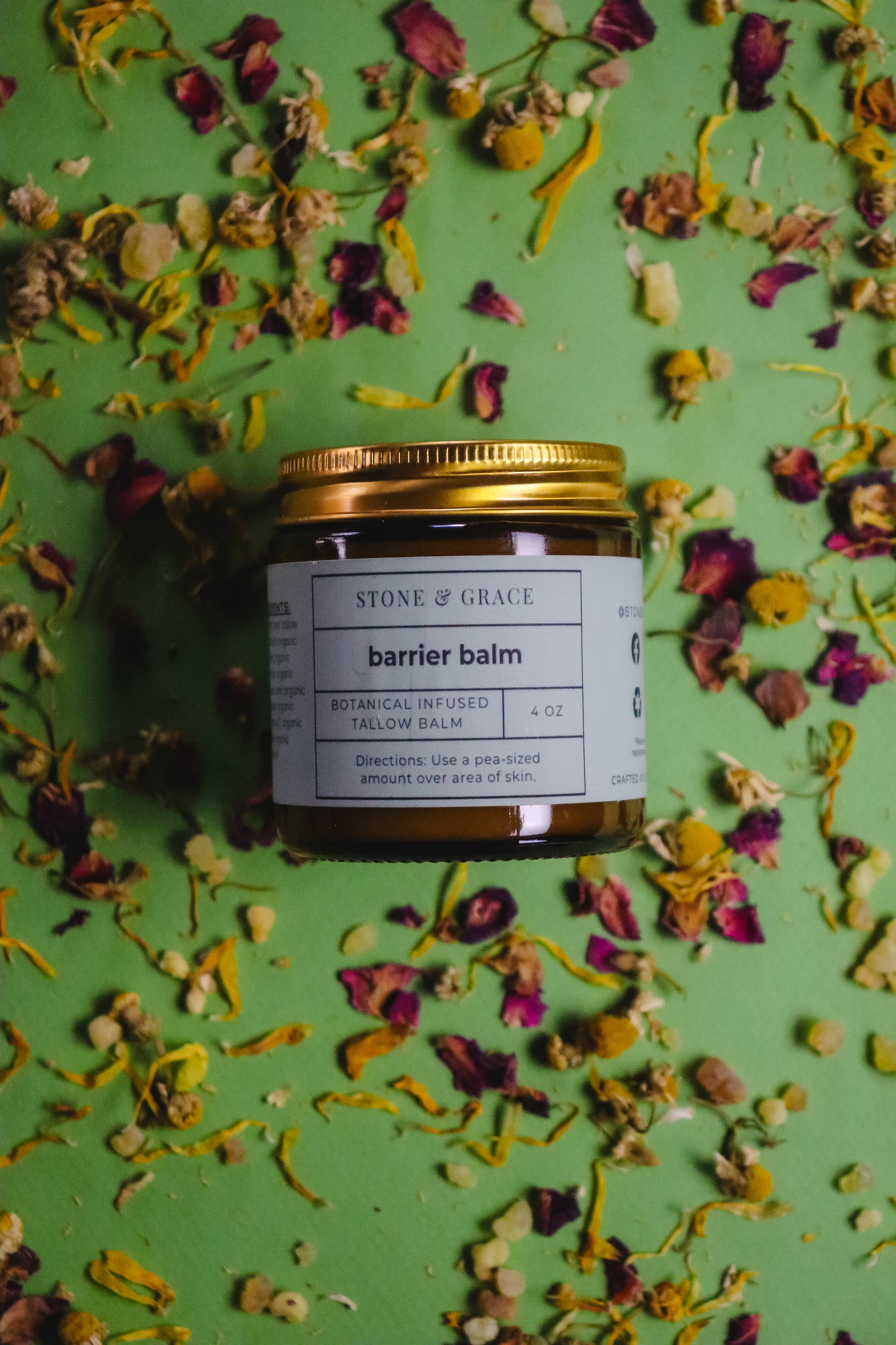 Jar of Stone & Grace Barrier Balm on a green background with dried flowers
