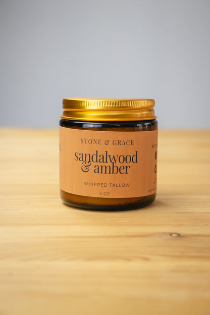 Jar of Sandalwood & Amber whipped tallow on a wooden surface with a gray background