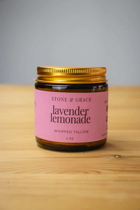 Jar of Stone & Grace lavender lemonade whipped tallow on a wooden surface with a gray background