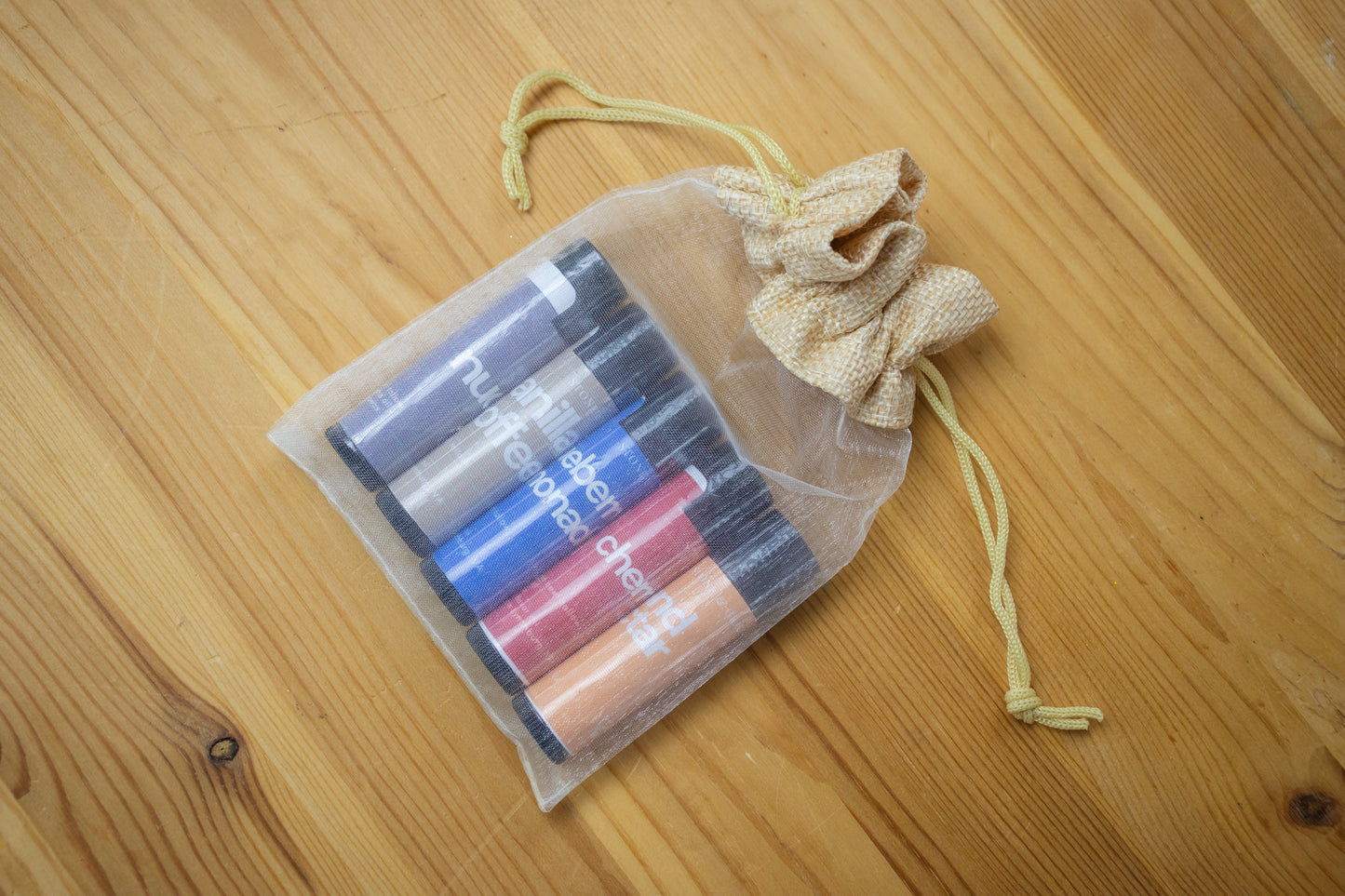 Set of tallow lip balm in a drawstring bag on a wooden surface